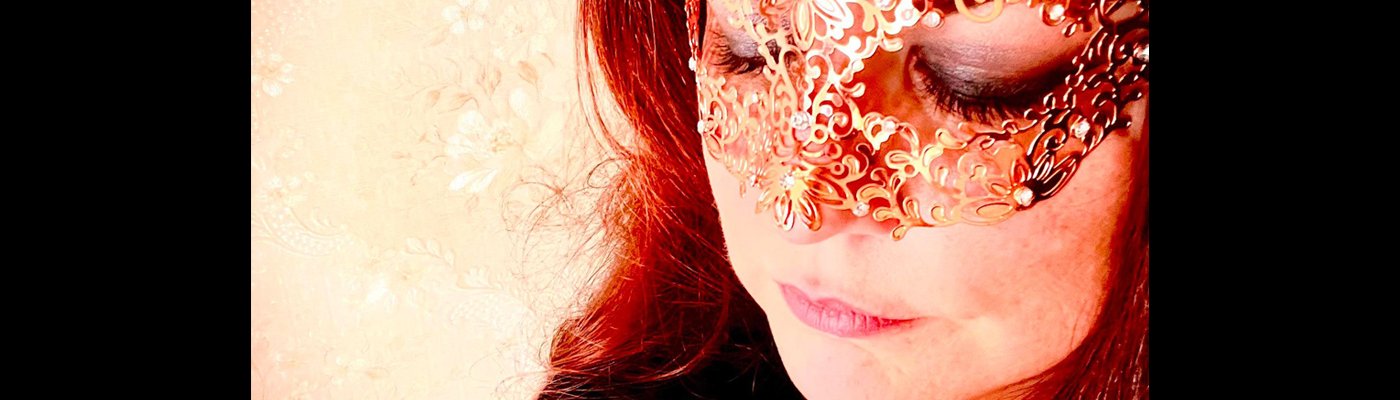 Color photograph of a woman wearing a rosegold lace mask across her eyes. 
